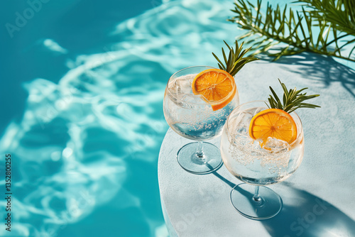 Sparkling cocktails with orange and ice on the table near the pool