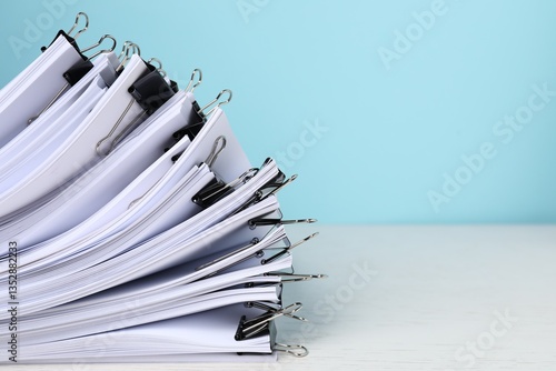 Binder clips with sheets of paper on white table, closeup. Space for text