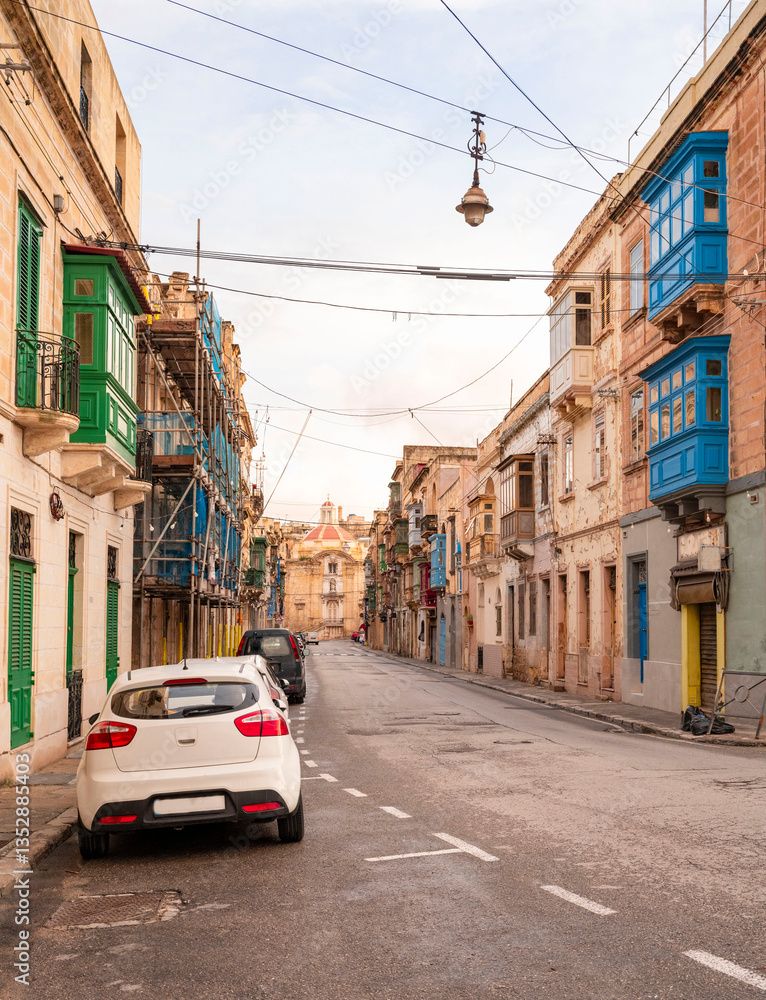 Obraz premium The nearly empty St. Margaret Street in Cospicua. Perhaps a reflection of the times. Triq Santa Margerita, Bormla.Cospicua,View at St Paul's Church Cospicua through a street with many colorful bay 