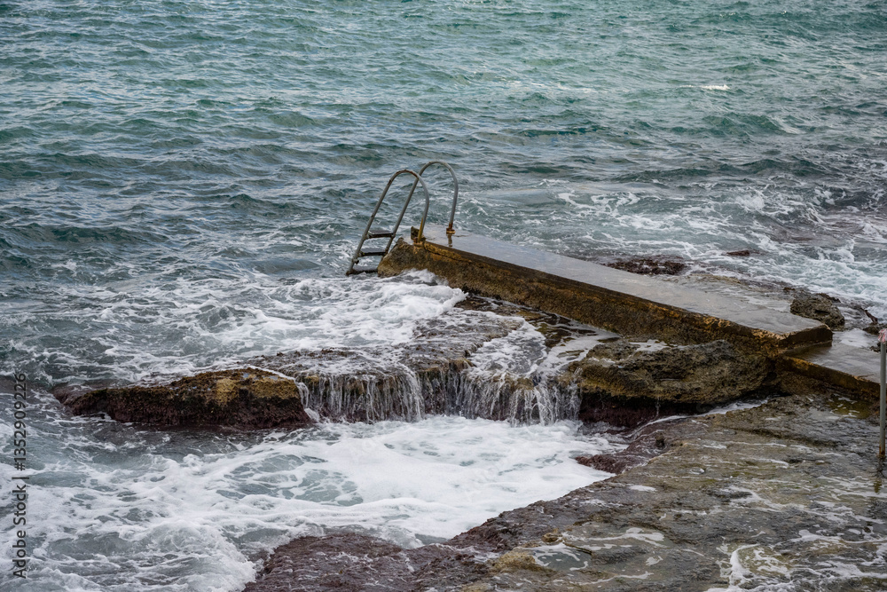 Fototapeta premium High Angle Shot of a Sea Waves Crashing on the Rocks. Rocks by the Sea North of Malta.