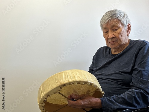 Blackfoot senior looking down at his drum