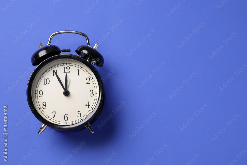 One black alarm clock on blue background, top view. Space for text One black alarm clock on blue background, top view. Space for text