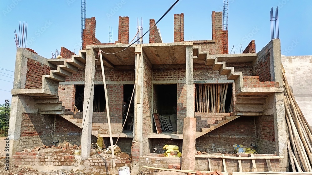 Obraz premium Workers are seen on a construction site where walls are taking shape with exposed bricks and scaffolding in bright daylight