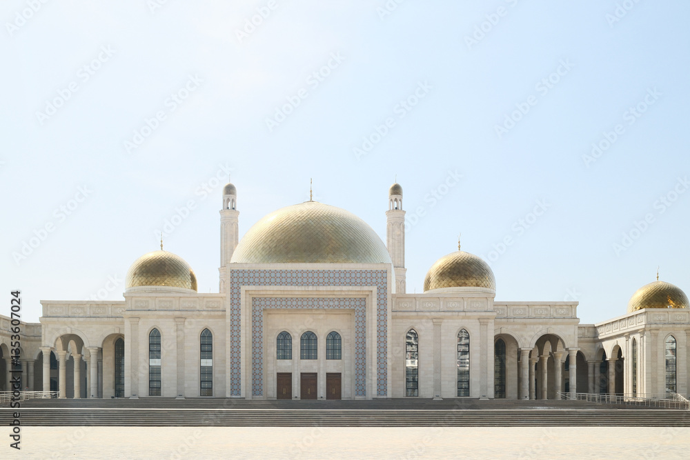Fototapeta premium A beautiful central city mosque in Almaty, Kazakhstan, with a golden dome and tall minarets under a clear sky