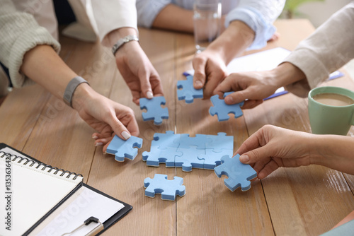 Unity concept. People putting puzzle pieces together at wooden table indoors, closeup