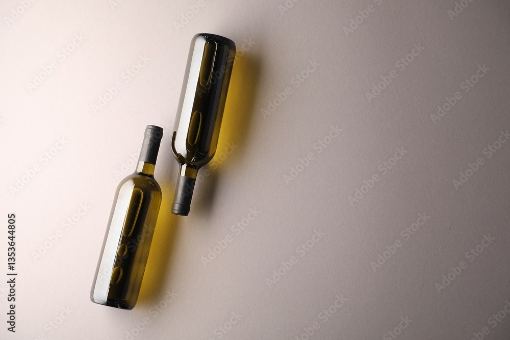 Naklejka premium Bottles of wine on light grey background, flat lay. Space for text
