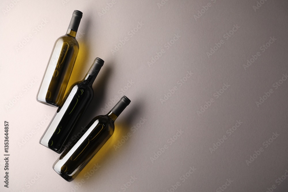 Naklejka premium Bottles of wine on light grey background, flat lay. Space for text