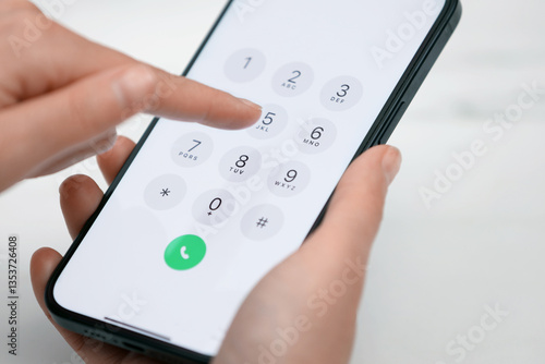 Billede på lærred Woman dialing number on smartphone against blurred background, closeup