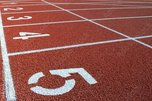Numbers on the red running track of the garden. White stripes and numbers on the red track, close-up. Starting field for sprint at the stadium. Running track at the stadium for competitions.