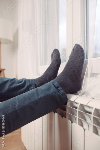 Obraz na płótnie Man's feet with socks on a home heating radiator on a cold winter day outdoors. w salonie
