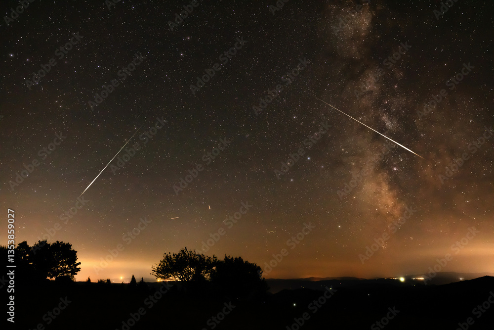 Milky way stars, meteor trails and landscape silhouettes.