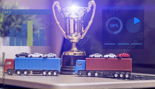 Toy cargo trucks carrying miniature cars on a laptop keyboard with a trophy and data graphs, symbolizing logistics, transportation, and market analysis