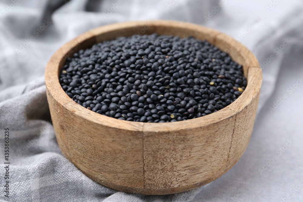 Black lentils in bowl on light table, closeup Black lentils in bowl on light table, closeup