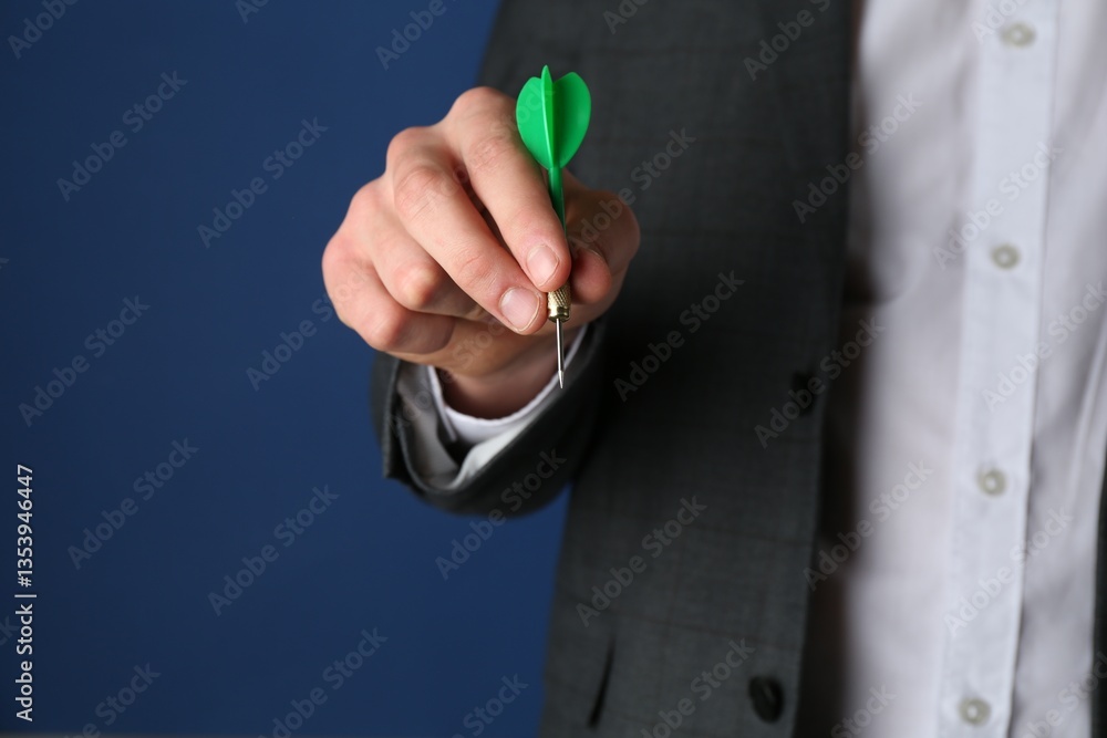 Fototapeta premium Man holding dart on blue background, closeup