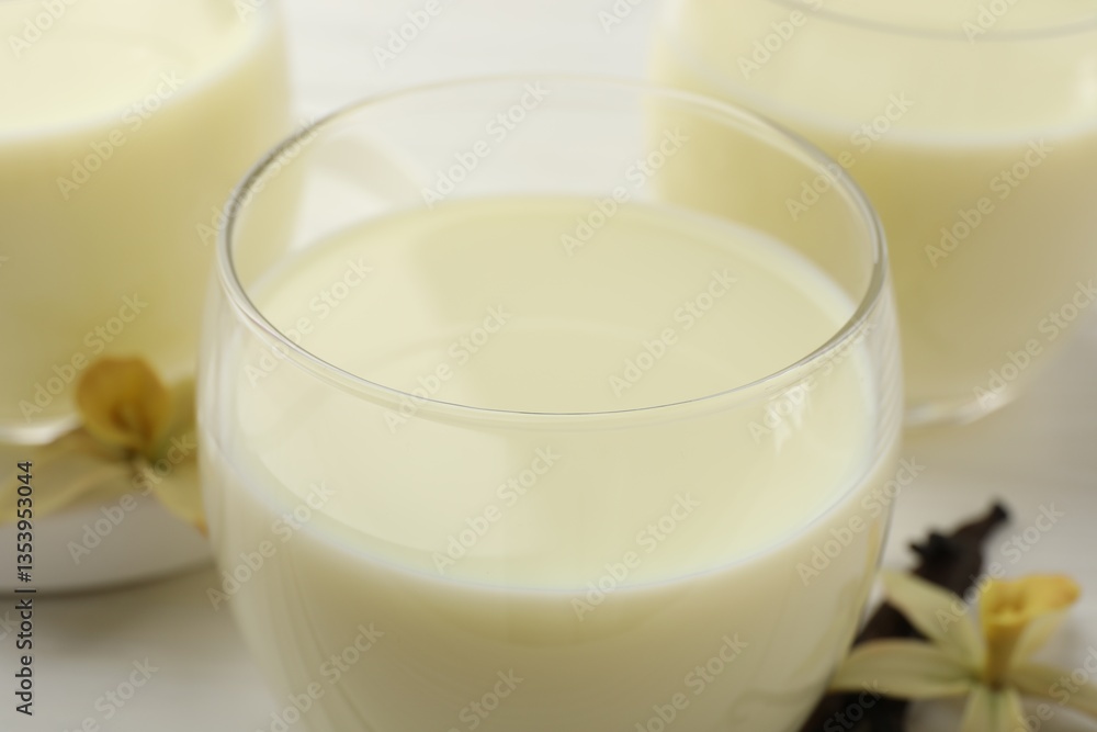Delicious vanilla milk in glasses on white table, closeup Delicious vanilla milk in glasses on white table, closeup