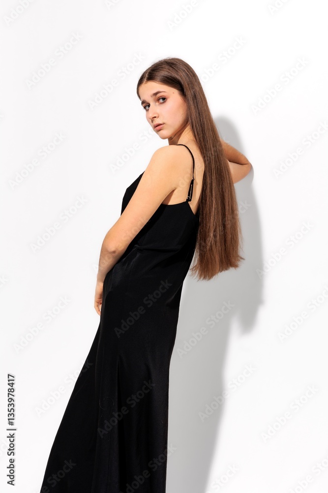 Elegant model posing in a sleek black dress against a minimalist white background in a studio setting Elegant model posing in a sleek black dress against a minimalist white background in a studio setting