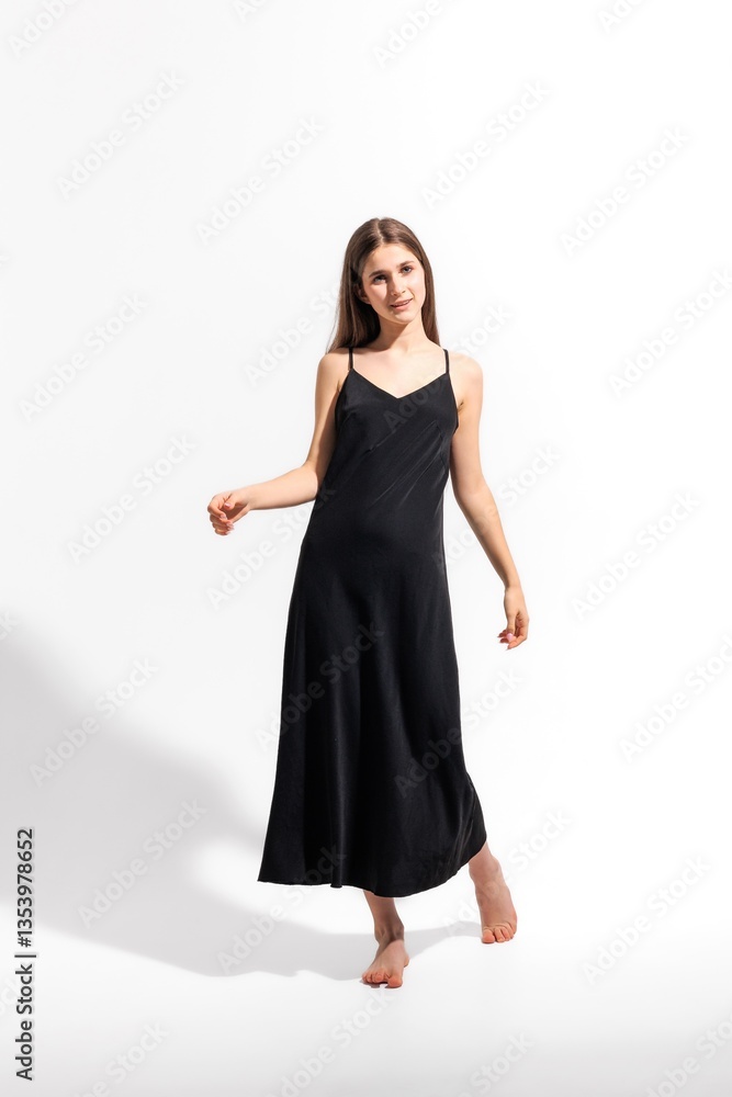 Elegant young woman poses in a black dress on a bright background in a stylish studio setting Elegant young woman poses in a black dress on a bright background in a stylish studio setting