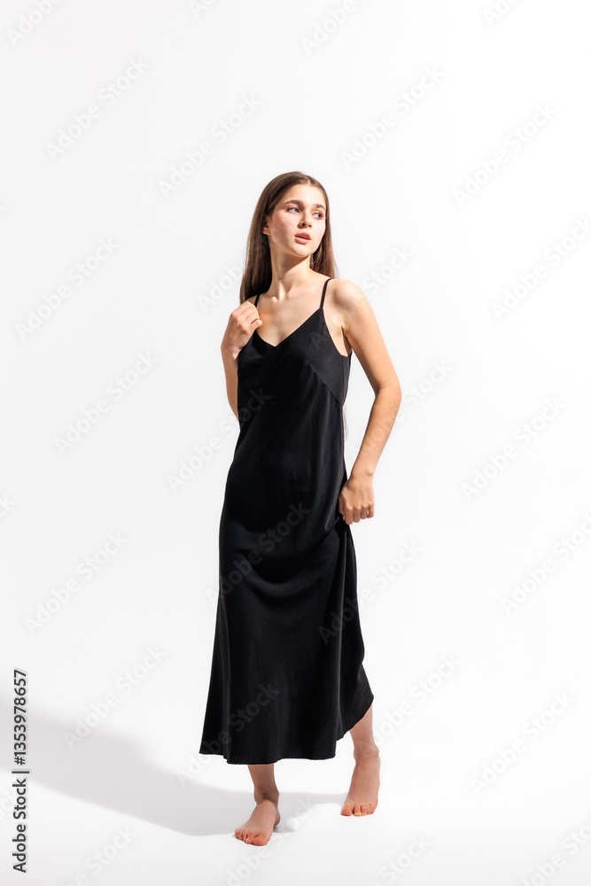 Model showcasing a simple black dress in a studio setting during a fashion photoshoot Model showcasing a simple black dress in a studio setting during a fashion photoshoot