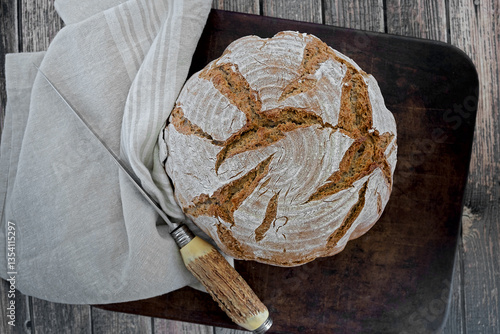 Homemade loaf of bread on a cloth and rustic stag horn knife
