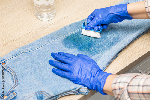 man cleaning jeans from dirt with a brush. woman removing dirty stain on jeans, close-up. dirty stain on jeans. man removes grease stain from clothes. 