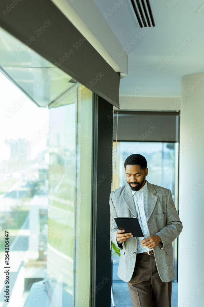 Fototapeta premium Professional man contemplating future while holding tablet in modern office setting