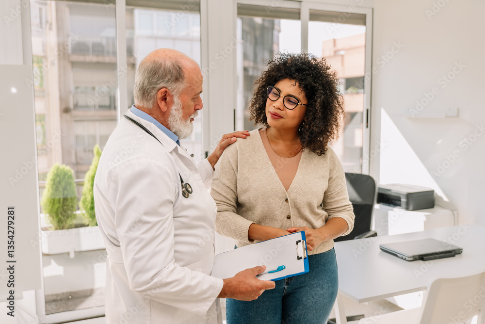 Fototapeta premium Senior male doctor comforting female Afro patient during medical consultation in clinic