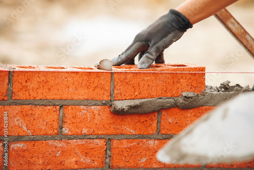 Tableau sur toile Close-up of hands of Skilled bricklayer laying bricks with precision