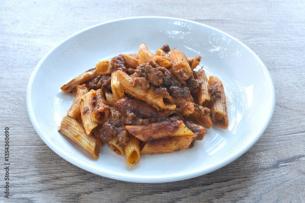 baking penne pasta topping mashed beef meat in sweet and sour sauce on plate baking penne pasta topping mashed beef meat in sweet and sour sauce on plate