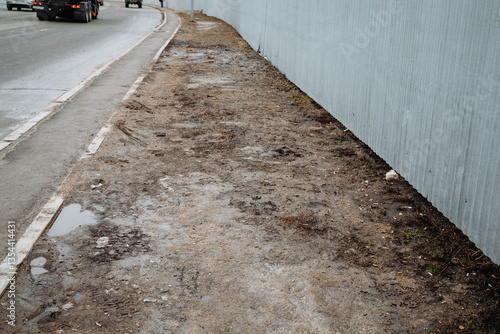 A large truck is driving steadily down a wide road that runs parallel to a sidewalk, highlighting the separation between vehicular traffic and pedestrian pathways for safety