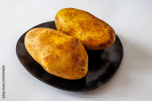 Fresh organic golden potatoes on a black plate