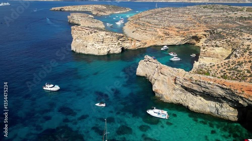 Aerial drone view of the Blue Lagoon on Comino Island, Malta. Panorama of the Mediterranean Sea, yachts, boats, and stunning cliffs.