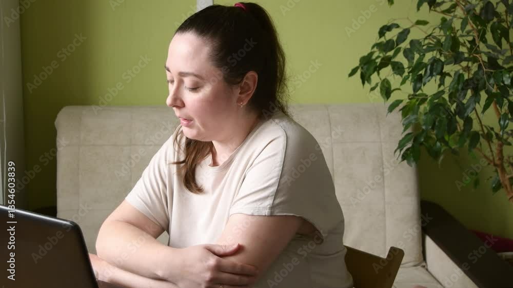Woman having online meeting with colleagues while working remotely from cozy home, highlighting freelance lifestyle and digital teamwork.