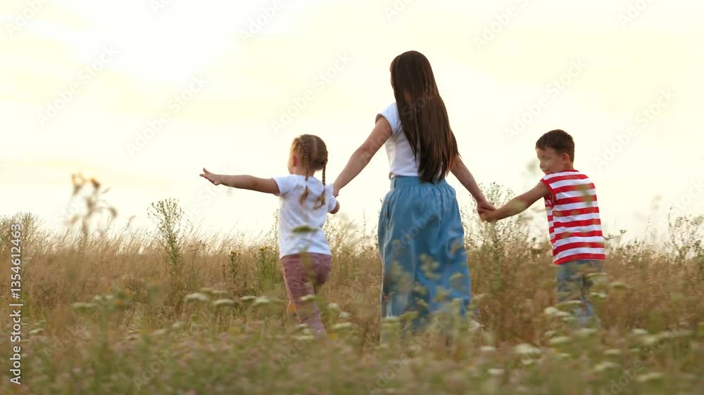 Happy mother with children runs playing plane in field grass at sunset time. Little children play with mother resting in country nature. Mother and sibling children spend summer vacation at rural side Happy mother with children runs playing plane in field grass at sunset time. Little children play with mother resting in country nature. Mother and sibling children spend summer vacation at rural side