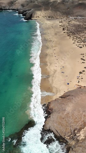 Aerial view of Papagayo Beach in Lanzarote, showcasing turquoise waters, golden sand, and dramatic volcanic cliffs.  

