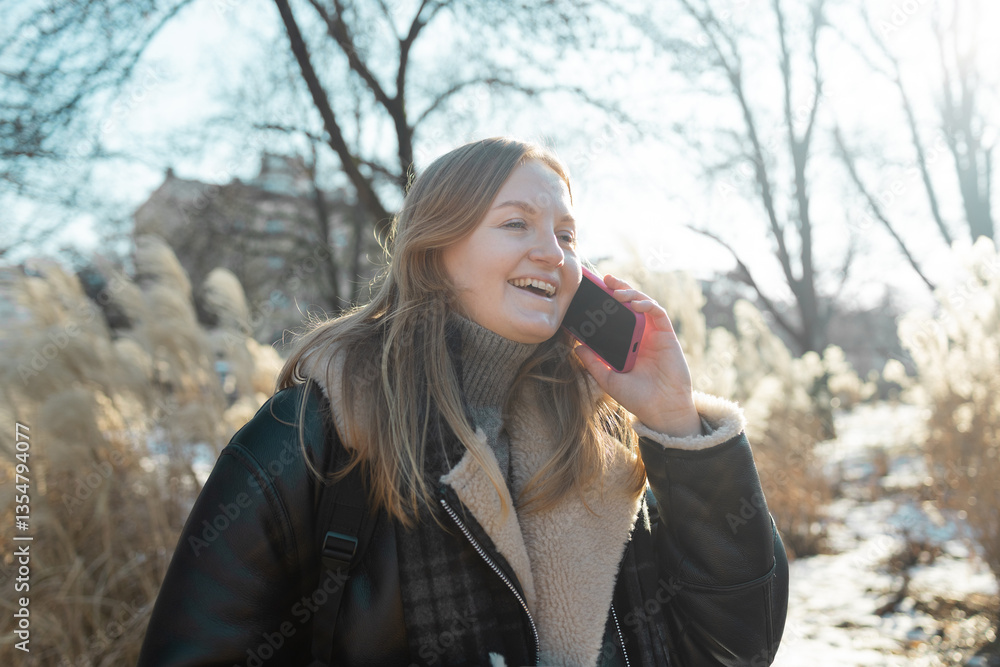 Happy smiling young woman portrait with phone enjoys winter weather at snowy winter park. High quality photo