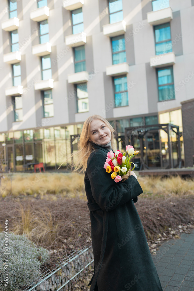 Beautiful happy Caucasian woman smelling bunch of tulips with closed eyes. High quality