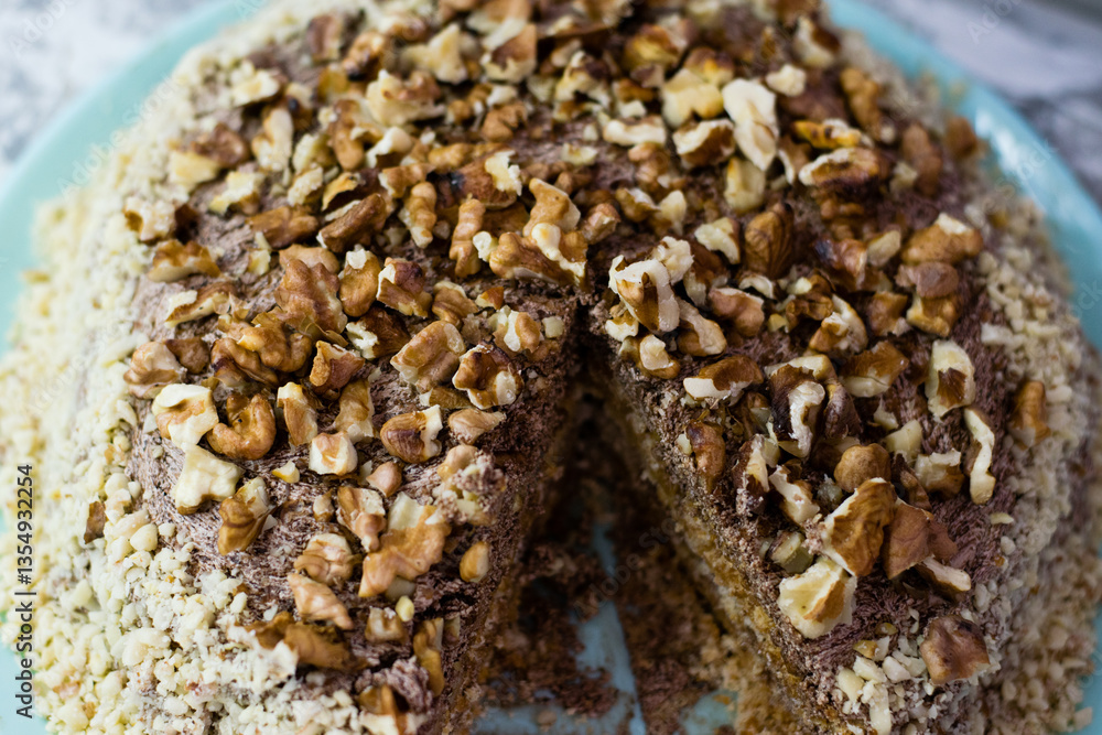 Delicious homemade cake with meringue, peanuts and walnuts on a light background. Sliced cake on a blue plate. Concept of natural homemade baking Delicious homemade cake with meringue, peanuts and walnuts on a light background. Sliced cake on a blue plate. Concept of natural homemade baking