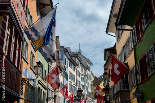 Swiss flags hanging between colorful buildings in lucerne