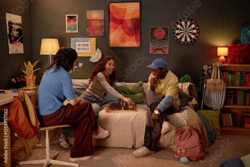 Group of friends gathered around small table playing chess in cozy, colorfully decorated room with posters and plants. Warm lighting creates relaxed and inviting atmosphere
