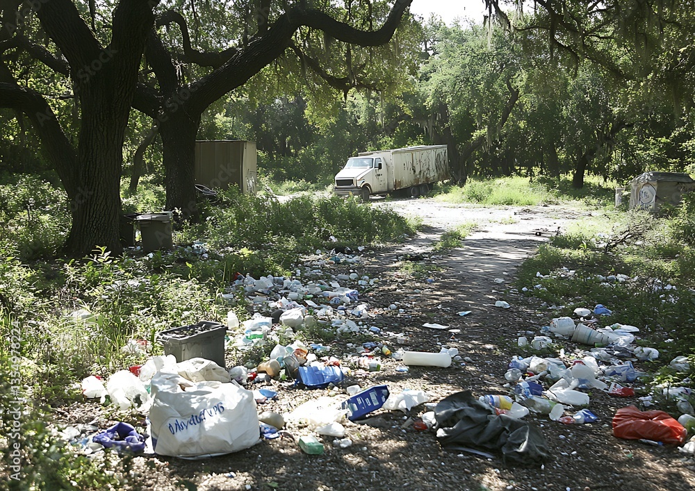 A garbage filled landscape with a truck and surrounding trees A garbage filled landscape with a truck and surrounding trees