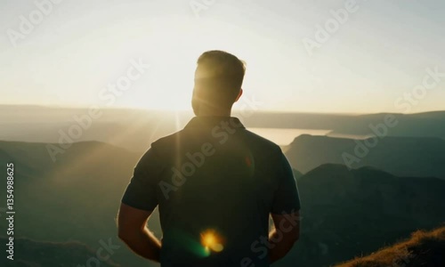 A man stands strong on a cliff’s edge, gazing toward the horizon with determination. The sky glows with the first light of dawn. Cinematic