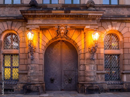 Fotografie Historic stone entrance with heavy arched wooden double doors, glowing wall lant