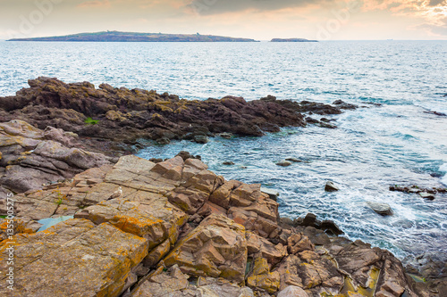Obraz na płótnie sea rock on the coast. travel nature background with stone on the shore. dramatic inspiration. beautiful summer vacation at the seaside. calm surface of blue water and evening sky in seascape w salonie