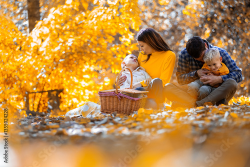Canvas Print Loving family with two young sons enjoying a cozy autumn picnic in the park