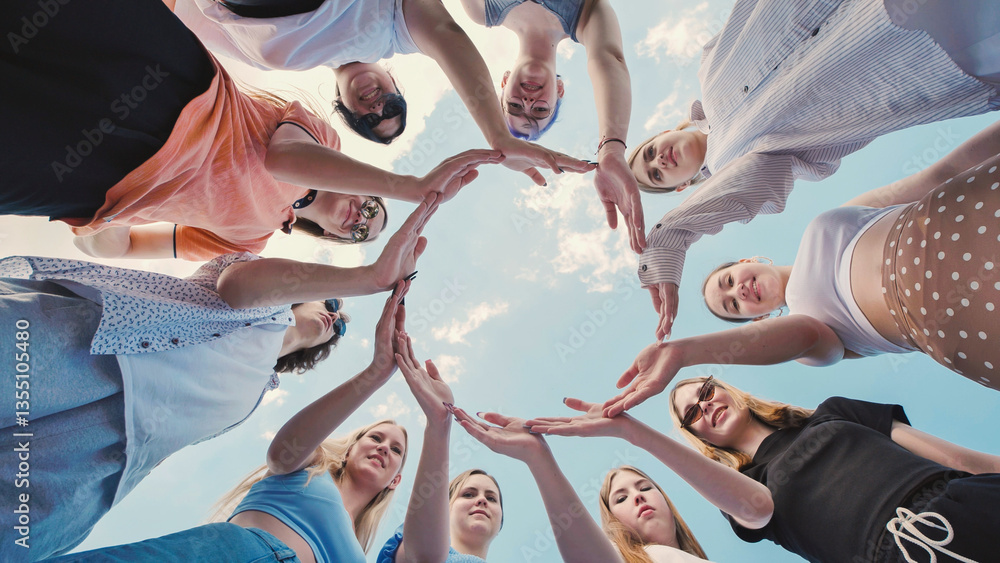 Obraz premium Group of school friends making a circle with their hands against a blue sky, symbolizing unity, teamwork and friendship