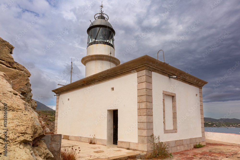 Coastal view of Far de Cala Nans lighthouse near Cadaques in Catalonia, Spain under cloudy skies
