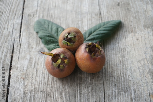 Three Ripe Medlar Fruits Placed on a Wooden Table in Natural Light