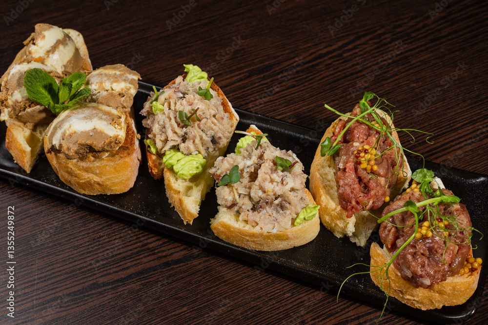 Three types of bruschetta on the table on a black plate beautiful serving in a restaurant. middle view