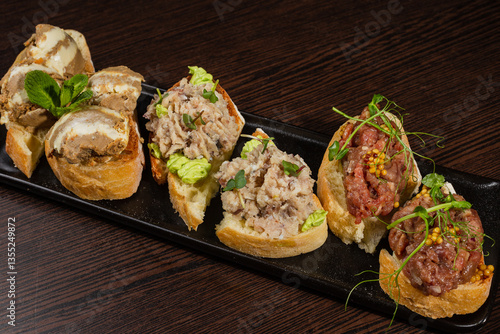 Three types of bruschetta on the table on a black plate beautiful serving in a restaurant. middle view