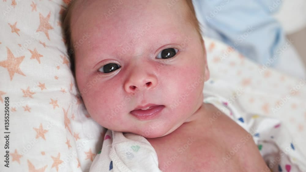 Newborn baby lying on a soft pillow and looking at the camera, cozy home atmosphere Newborn baby lying on a soft pillow and looking at the camera, cozy home atmosphere